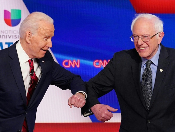 El ex vicepresidente Joe Biden choca su codo con Bernie Sanders en uno de los últimos debates demócratas.(Mandel NGAN/AFP)