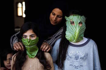 Una madre intenta proteger a sus hijos con máscaras de hojas de coliflor, en Gaza.(Mohamed ABED/AFP)