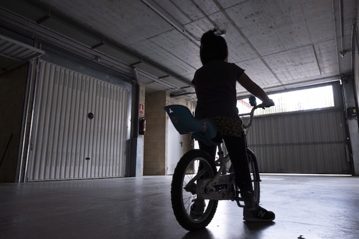 Una niña en bicicleta, ante la puerta del garaje. (Jon URBE/FOKU)