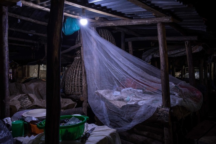 Un comerciante duerme en un mercado de Kampala (Uganda) con una mosquitera para progerse de la malaria. (Badru KATUMBA/AFP)