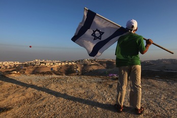 Un israelí agita su bandera con la vista puesta en la colonia de Maale Adumim, en Jerusalén Oriental.MENAHEM KAHANA  | AFP