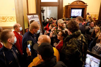La Policía del Estado de Michigan trata de frenar a los manifestantes en el interior del Capitolio de Lansing. (Jeff KOWALSKY/AFP)
