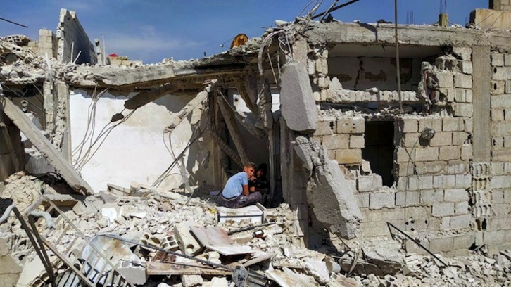 Dos jóvenes, sentados entre los escombros de un edificio de Damasco tras un bombardeo de Israel el 27 de abril. (AFP)