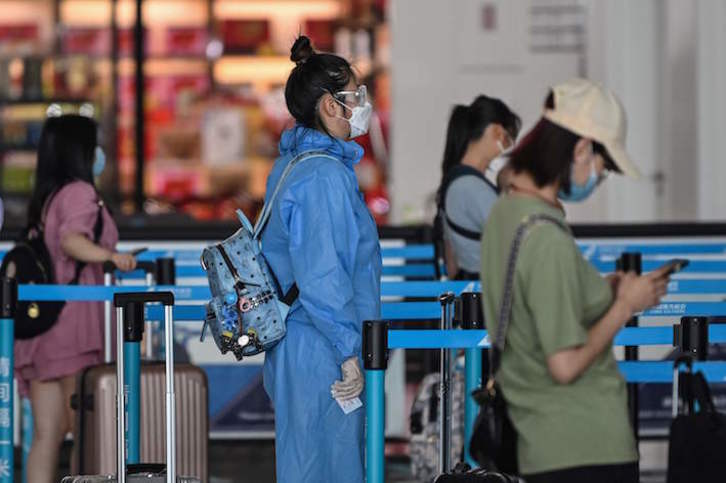 Una pasajera se dispone a coger un vuelo en el aeropuerto de Wuhan con múltiples medidas de protección. (Hector RETAMAL/AFP) 