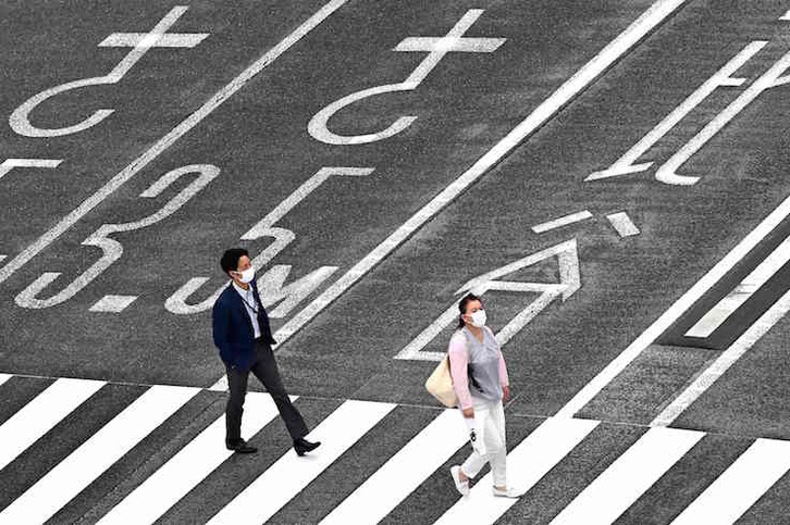 Dos personas caminan por un paso de cebra del centro de Tokio. (Charly TRIBALLEAU/AFP)
