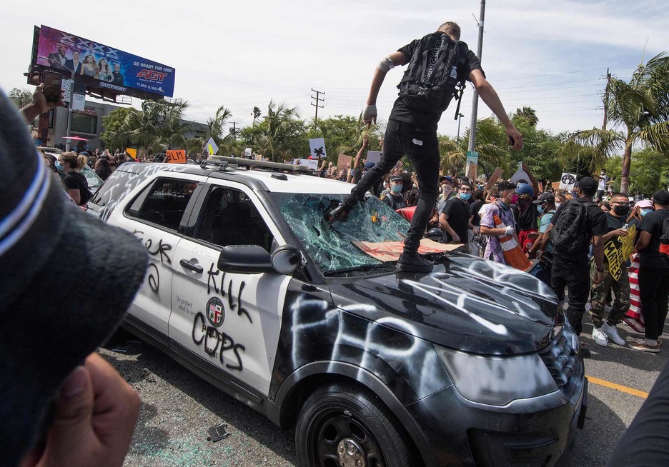 Los manifestantes destrozan un vehículo policial en el distrito de Fairfax (Los Ángeles) mientras protestan por la muerte de George Floyd. (Mark RALSTON/AFP)