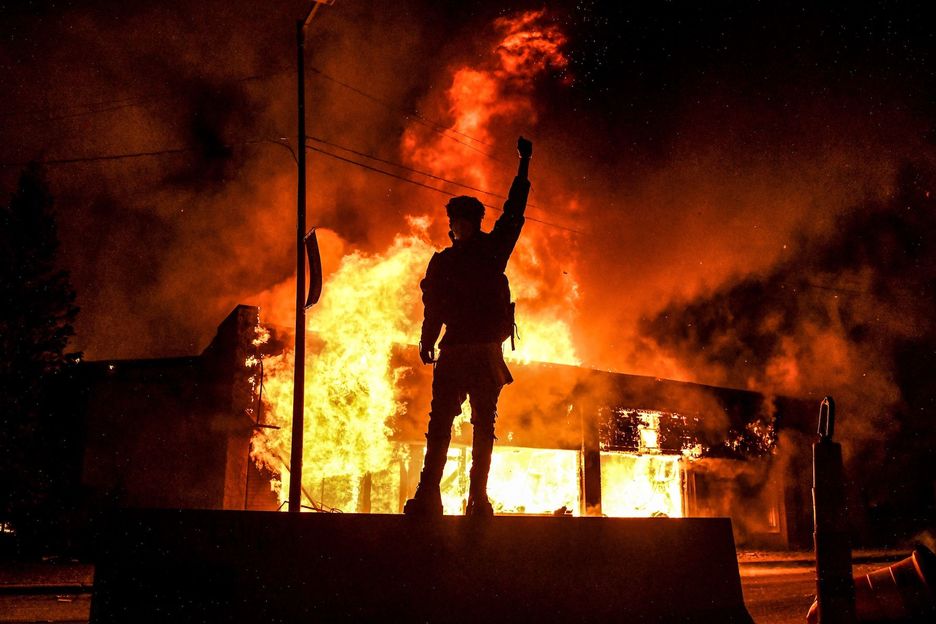 Un manifestante se planta ante un edificio incendiado durante una manifestación en Minneapolis, Minnesota. (Chandan KHANNA/AFP)