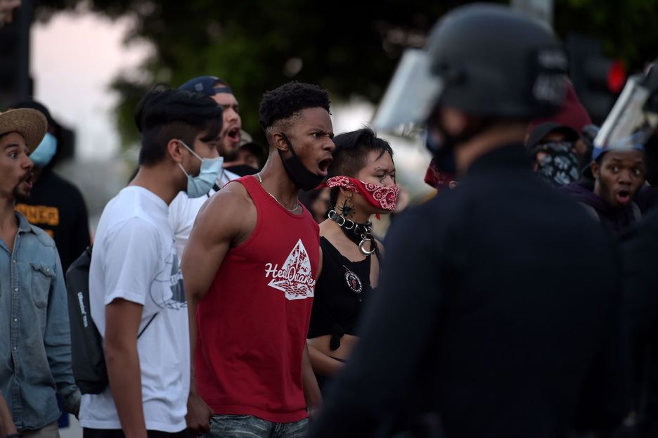 Los manifestantes reaccionan frente a la policía mientras se reúnen en el centro de Los Ángeles. (Agustin PAULIER/AFP)