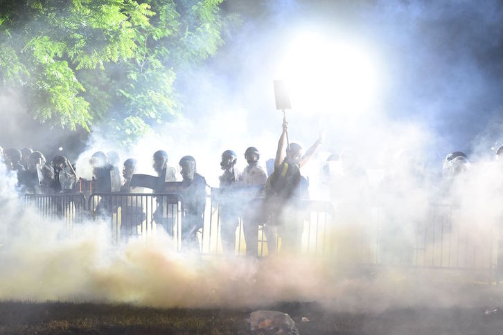 Un manifestante pasa entre el humo y delante de la Policía en las inmediaciones de la Casa Blanca. (ROBERTO SCHMIDT / AFP) 