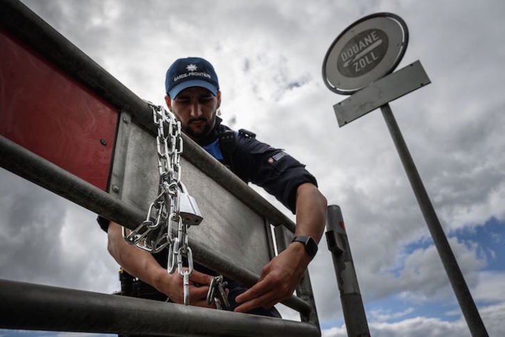 Un oficial de aduanas suizo abre la frontera franco-suiza, cerrada a causa de la pandemia. (Fabrice COFFRINI/AFP)