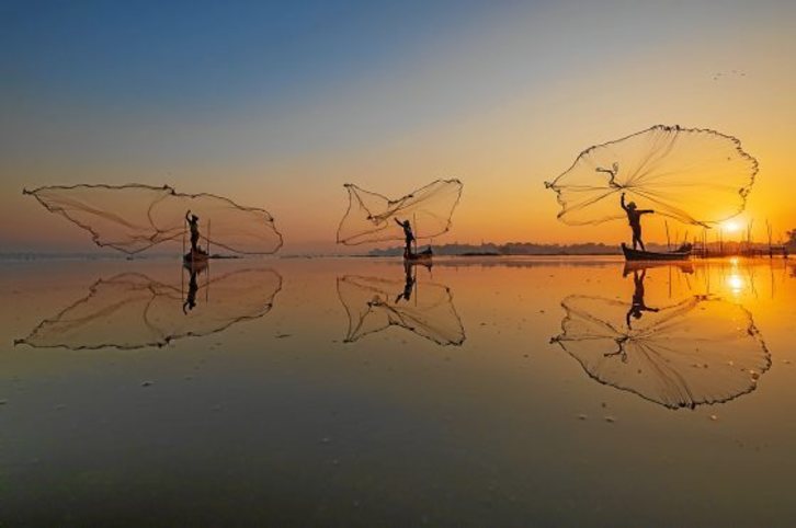 Bajo el significativo título de «Trae a casa la cosecha», tres pescadores birmanos lanzan sus redes en un lago cercano al puente U Bein en Mandalay (Myanmar). Fotografía: Zay Yar Lin|Pink