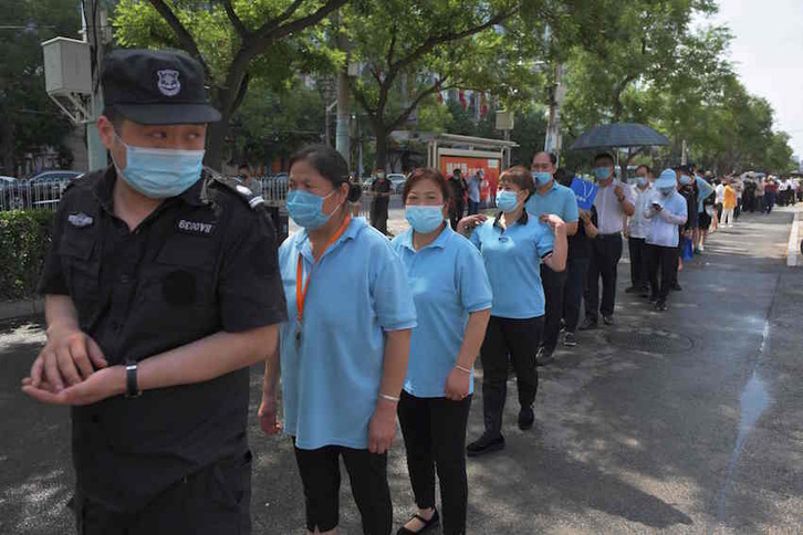 Un grupo de personas aguarda a que le hagan el test de coronavirus en Pekín. (Greg BAKER/AFP)