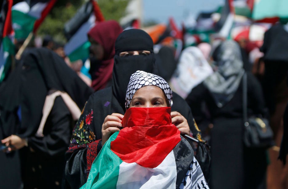 Emakume batek Palestinako bandera jarri dio beste bati Gazan egidako mobilizazioan. (Mohammed ABED/AFP)