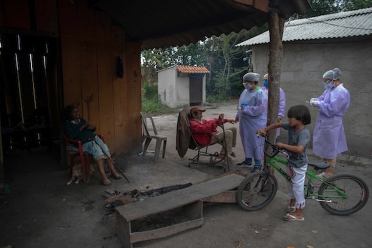 Profesionales de la salud administran pruebas COVID-19 a una pareja de ancianos en el campamento de la tribu Sao Mata Verde Bonita, en tierras indígenas guaraníes. (Mauro PIMENTEL/AFP)