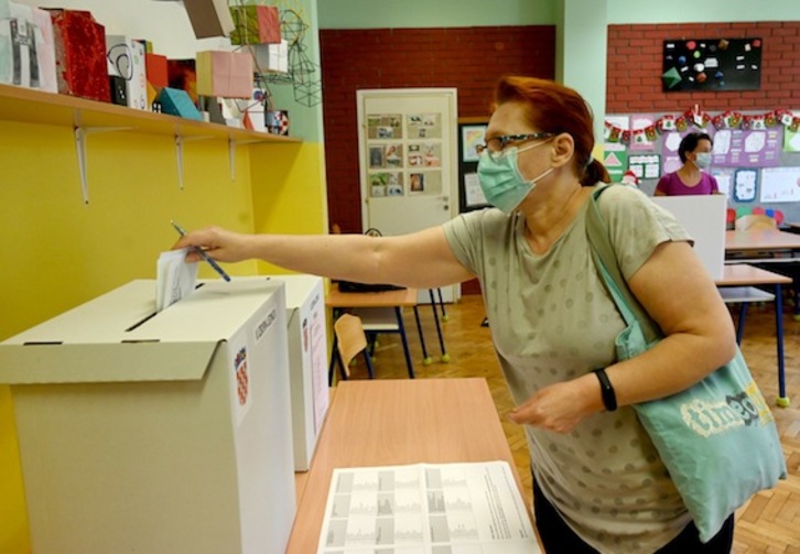 Una mujer deposita su voto en un colegio electoral de Zagreb. (Denis LOVROVIC/FOKU)