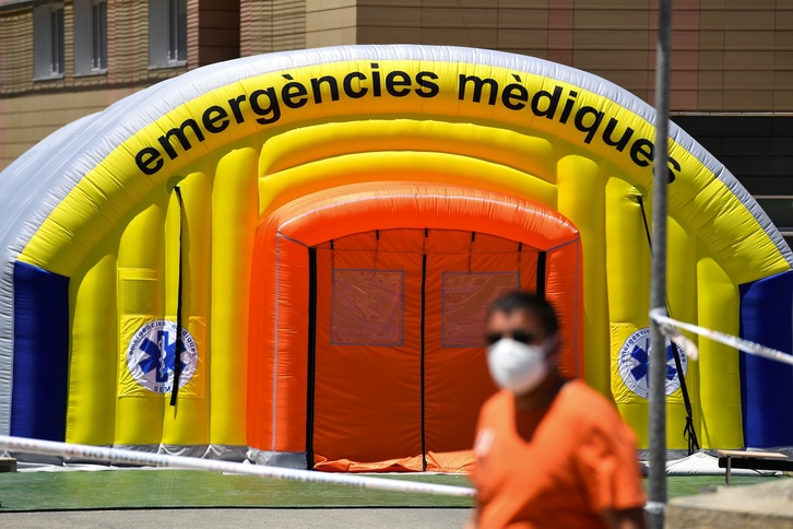 Un hombre con una máscara facial pasa frente a un hospital de campaña establecido para casos de coronavirus fuera del Hospital Universitario Arnau de Vilanova en Lleida. (Pau BARRENA/AFP)