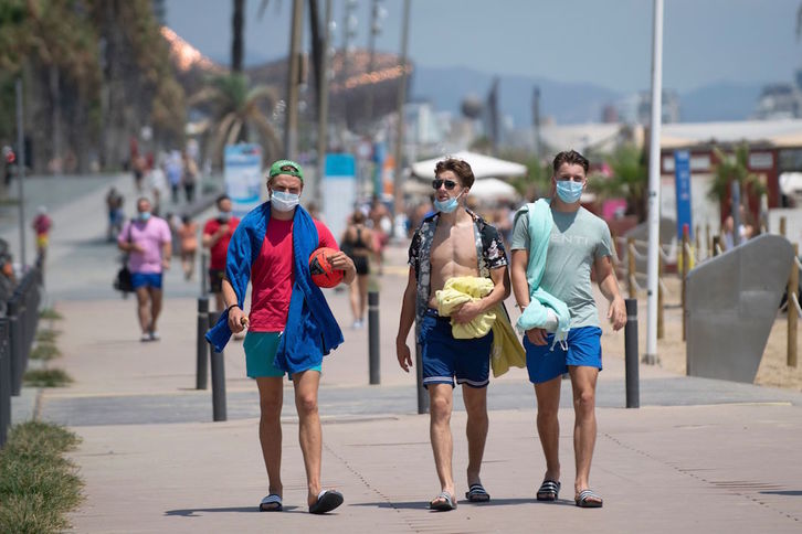 Jóvenes pasean en la playa de Barcelona. (Josep LAGO/AFP)