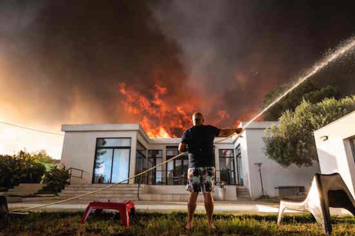 Un hombre trata de salvar su casa de las llamas. (Xavier LEOTY / AFP)