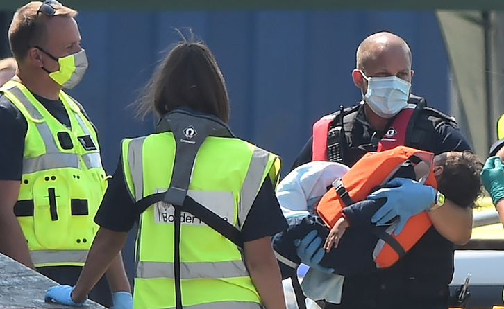 Un guardacostas británico lleva un niño inmigrante en Dover. (Gleen KYRK | AFP)