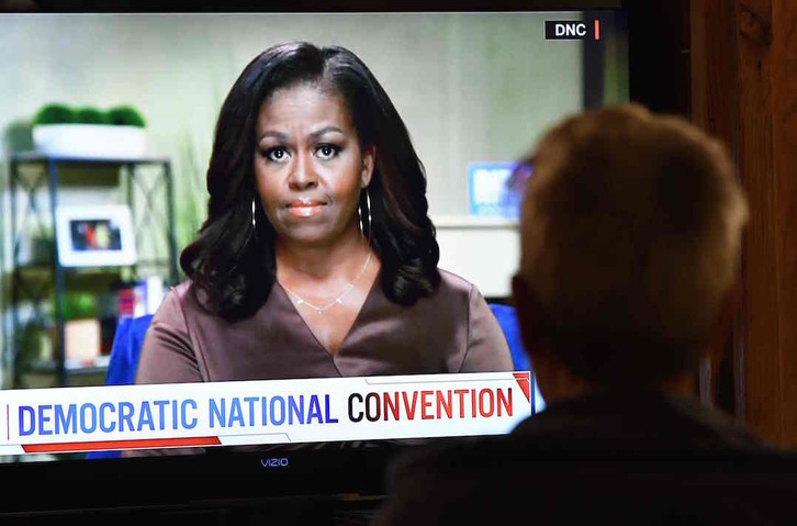 Una persona ve por televisión la intervención de Michelle Obama en la convención demócrata, que se desarrolla de manera virtual por el coronavirus. (Chris DELMAS/AFP)