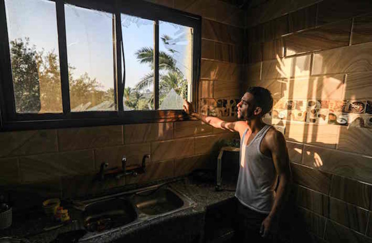 Un gazatí observa los cristales rotos por un ataque aéreo de Israel. (Mahmud HAMS/AFP)