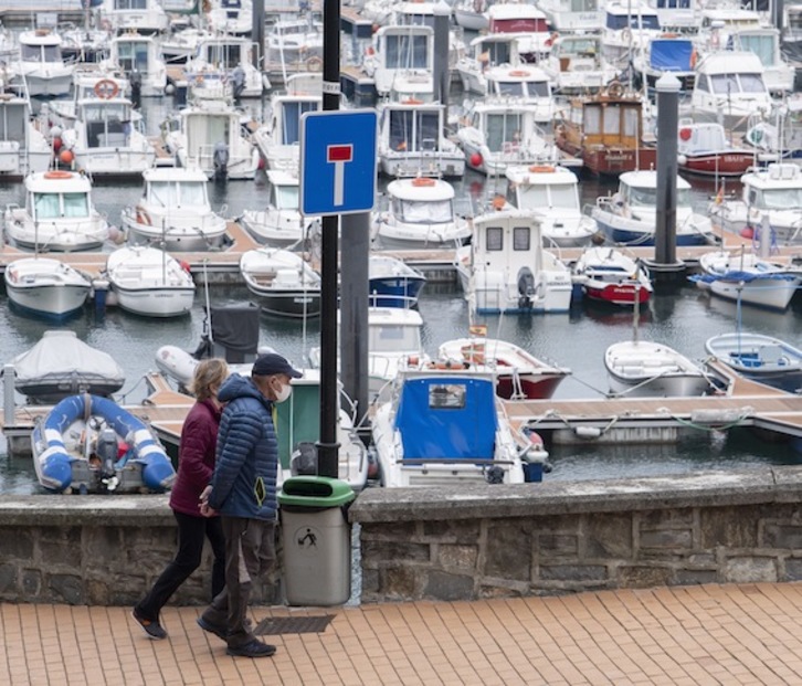Mutrikuko portuan bi herritar paseatzen, lehen fasera pasatu berritan, maiatzean. (Jon URBE / FOKU)