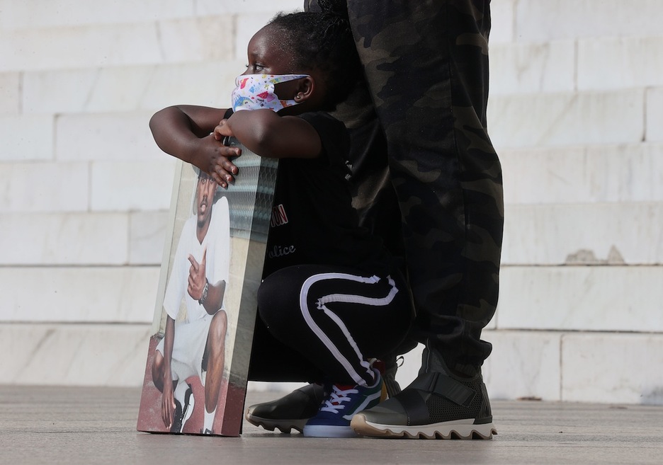La hija de Marqueese Alston, asesinado por la policía de Washington en 2018, con un cuadro de su padre en la protesta celebrada en la capital estadounidense. (Jonathan ERNST/AFP)