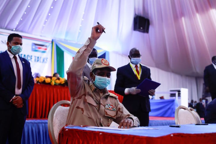 El hombre fuerte en el poder en Sudán, Mohamed Ahmad Dagalo, levanta el bolígrafo antes de la firma. (Akuot CHOL/AFP)