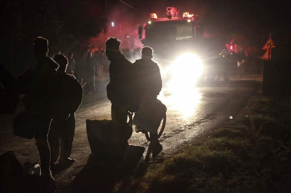 Suhiltzaileak kanpamentuan, migratzaile eta errefuxiatuen begiradapean. (Manolis LAGOUTARIS/AFP) Suhiltzaileak kanpamentuan, migratzaile eta errefuxiatuen begiradapean. (Manolis LAGOUTARIS/AFP)