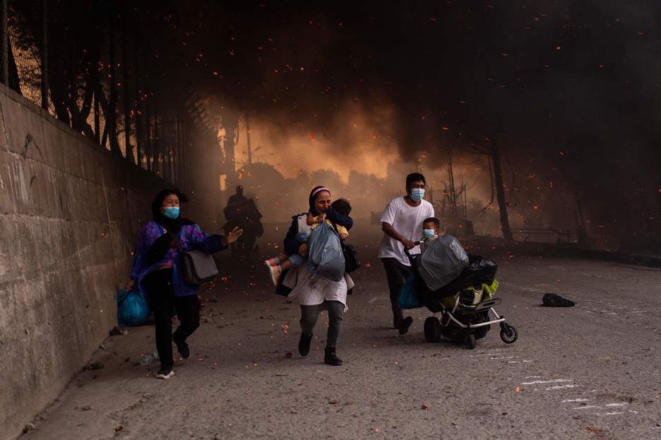 Refugiados en Moria huyen con sus hijos tras declararse el segundo incendio. (Angelos TZORTZINIS/AFP) Refugiados en Moria huyen con sus hijos tras declararse el segundo incendio. (Angelos TZORTZINIS/AFP)