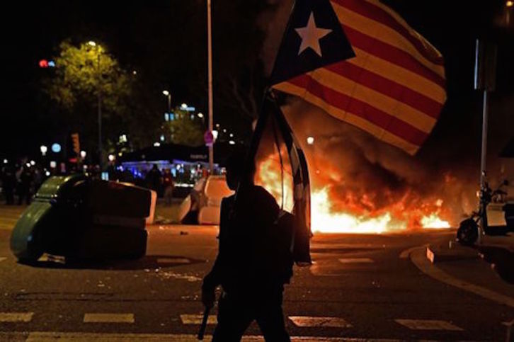 Un manifestante con una estelada frente a una barricada de fuego en Barcelona. (Josep LAGO/AFP)
