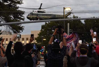 Simpatizantes de Trump observan el helicóptero en el que ha sido trasladado del hospital a la Casa Blanca. (OLIVIER DOULIERY / AFP)