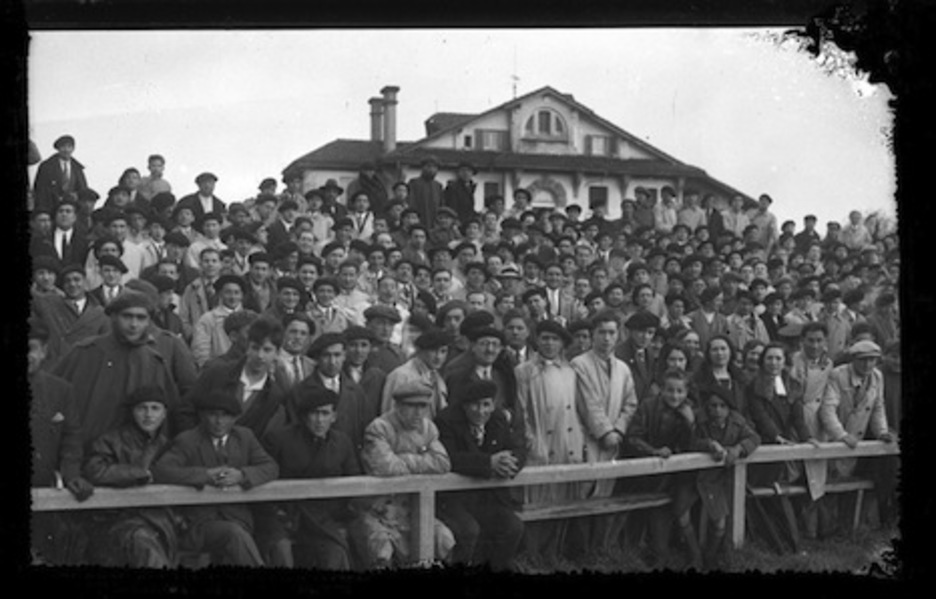Nutrido grupo de espectadores presenciando un partido de los rojillos. Al fondo se ve el antiguo edificio de la Clínica San Miguel. (José GALLE/FOTOTECA DE NAFARROA)