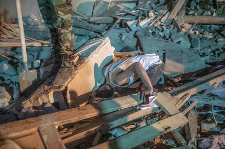 Un hombre busca supervivientes entre los escombros de la zona bombardeada. (Bulent KILIC / AFP)