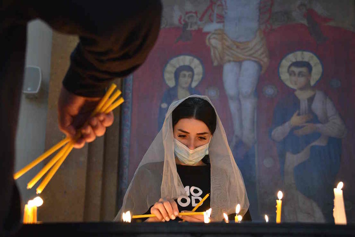 Una mujer armenia en una iglesia de Ereván rezando por los muertos tras el anuncio del frágil alto el fuego. (Karen MINASYAN/AFP)