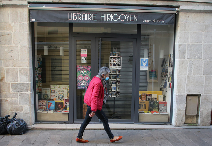 Una mujer camina junto a una librería cerrada, por el confinamiento,  en el centro de Baiona. (Bob EDME)