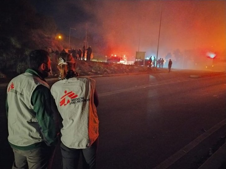 Dos integrantes de Médicos Sin Fronteras observan el resplandor de las llamas. (@MSF_Sea)