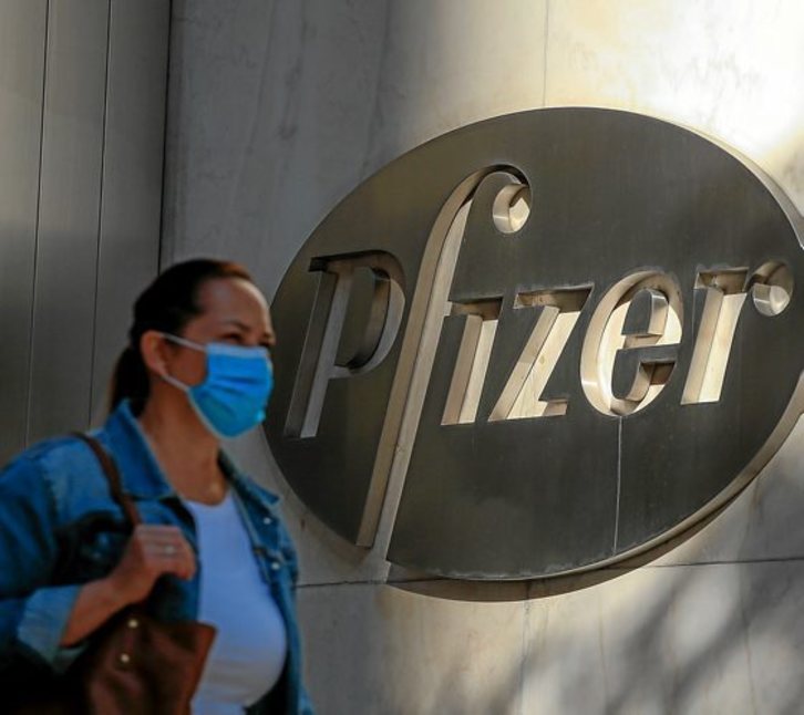 Una mujere con mascarilla, ante la sede de Pfizer en Nueva York. (Kena BETANCUR/AFP)
