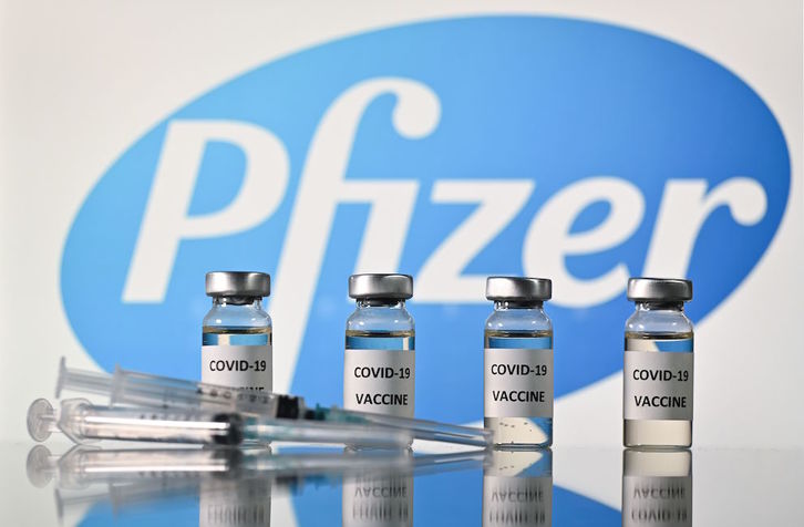 Frascos con adhesivos de vacuna covid-19 y el logotipo de Pfizer. (Justin TALLIS/AFP)