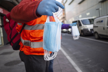 Un voluntario reparte mascarillas quirúrgicas desechables al inicio de la pandemia. (Endika PORTILLO/FOKU)