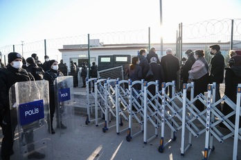 Poliziak Sincaneko kartzelan egin den epaiketa egoitzara akusatuen senideen sartzeko unea behatzen du (STRINGER/AFP) 