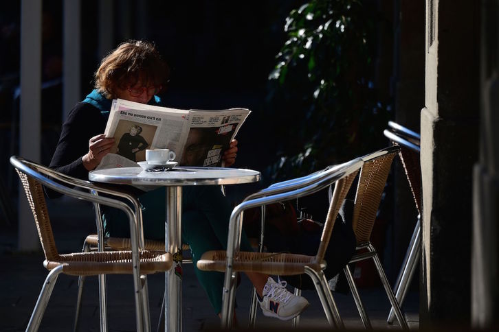 Una mujer lee el periódico en una terraza en Barcelona tras la apertura de la hostelería. (Lluis Gene/AFP)