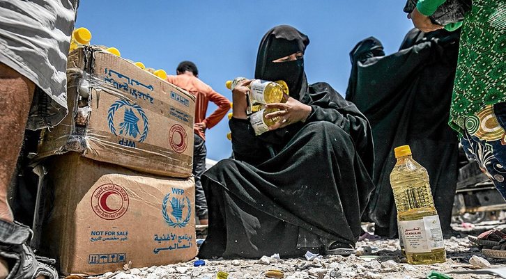 UNa mujer sostiene alimentos distribuidos por la ONU en un campo de desplazados en Siria. (Delil SOULEIMAN / AFP)