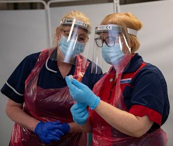 Dos enfermeras británicas con una dosis de Pfizer antes de inyectarla en Yorkshire. (ANDY STENNING/AFP)
