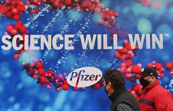 Personas con mascarilla pasan junto a las oficinas de Pfizer en Nueva York. (Angela WEISS/AFP)