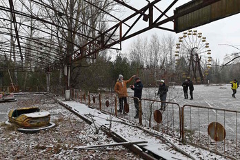 Turistas, junto a un parque de atracciones abandonado de la ciudad de Prípiat. (Genya SAVILOV/AFP)