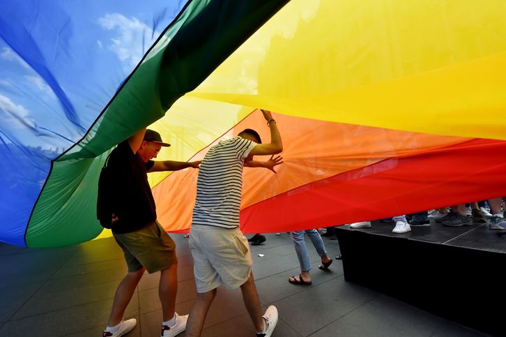 Dos personas pasan por debajo de la bandera LGTB. (Attila KISBENEDEK/AFP)