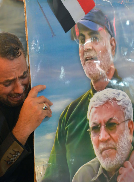 Un manifestante llora con los retratos de Mohandis y Soleimani. (Ali NAJAF | AFP)