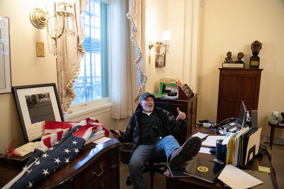 Un partidario de Trump se sienta dentro de la oficina del presidente de Estados Unidos. (Saul LOEB/AFP)