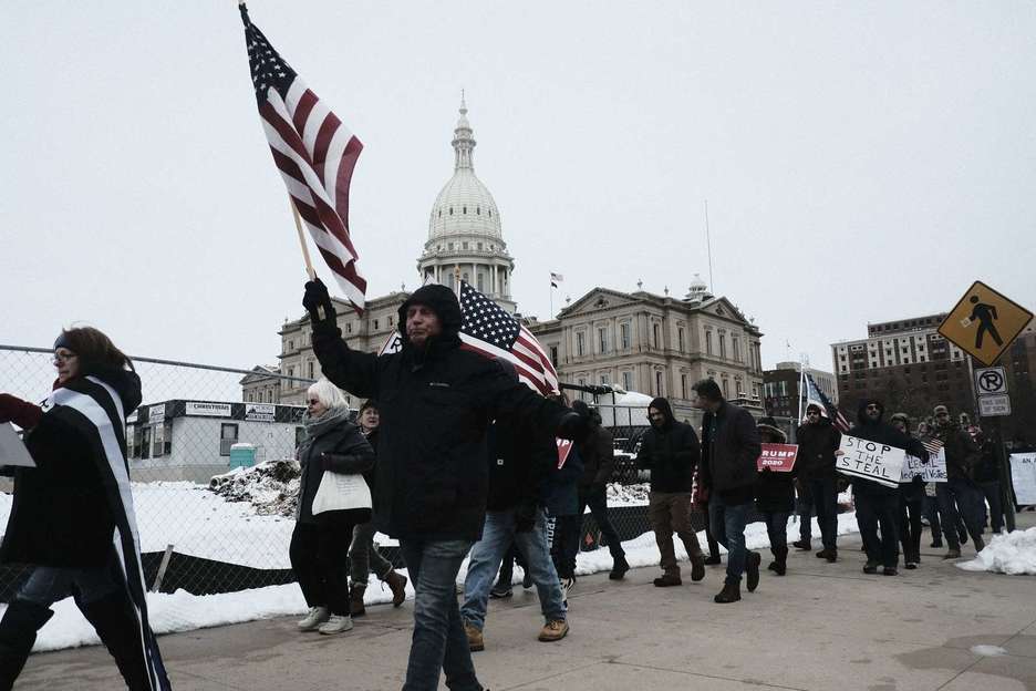 Cientos de partidarios de Donald Trump marchan alrededor del Edificio del Capitolio Estatal de Michigan. ( Matthew HATCHER/AFP)